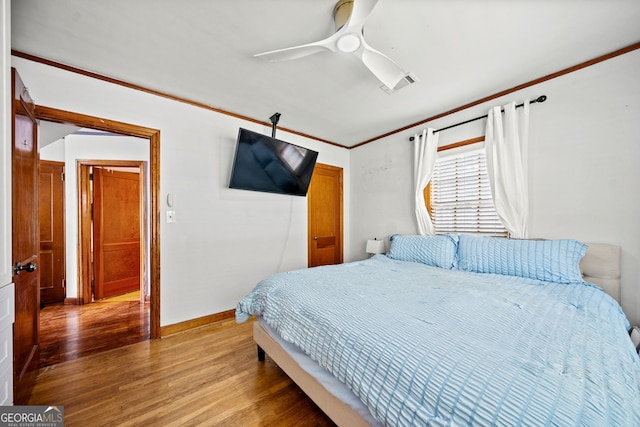 bedroom with hardwood / wood-style flooring, ceiling fan, and crown molding