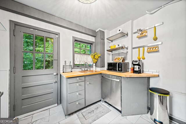 kitchen with appliances with stainless steel finishes, butcher block counters, sink, and gray cabinetry