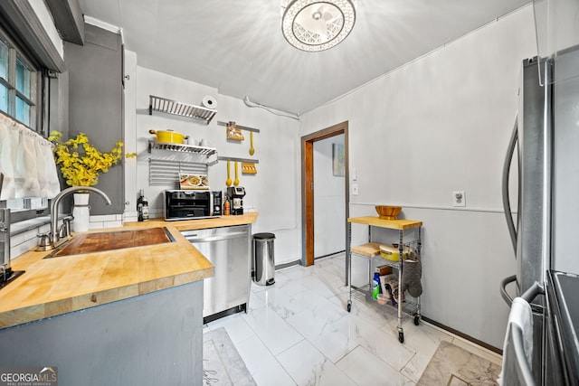 kitchen with wooden counters, stainless steel appliances, and sink