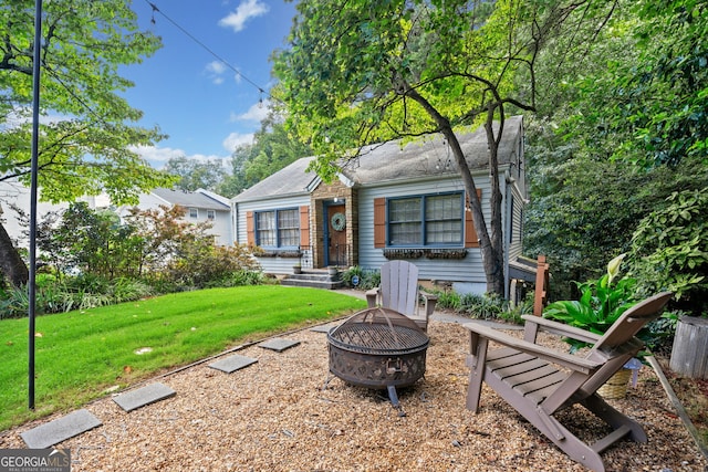 exterior space featuring an outdoor fire pit and a front yard