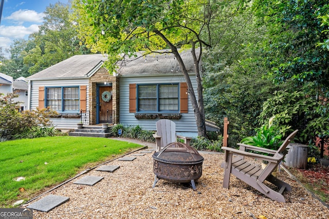 bungalow with a front lawn and a fire pit