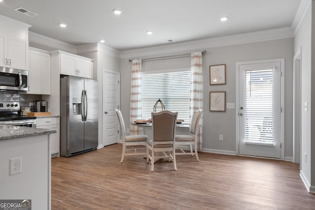 dining room with crown molding and light wood-type flooring