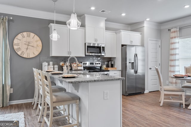 kitchen featuring sink, hanging light fixtures, appliances with stainless steel finishes, light stone countertops, and white cabinets