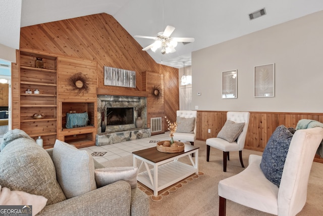 living room with high vaulted ceiling, a fireplace, wood walls, light colored carpet, and ceiling fan