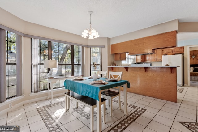 tiled dining space with a notable chandelier and a textured ceiling