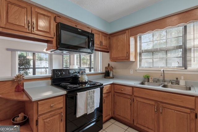 kitchen featuring sink, a wealth of natural light, light tile patterned floors, and black appliances