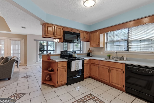 kitchen with light tile patterned flooring, black appliances, sink, kitchen peninsula, and french doors