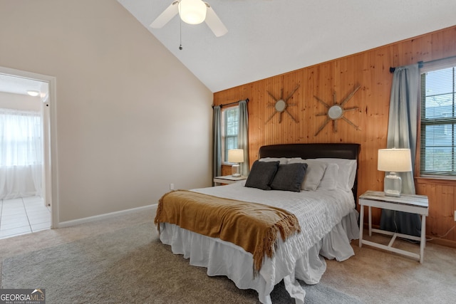 carpeted bedroom with wooden walls, high vaulted ceiling, and ceiling fan