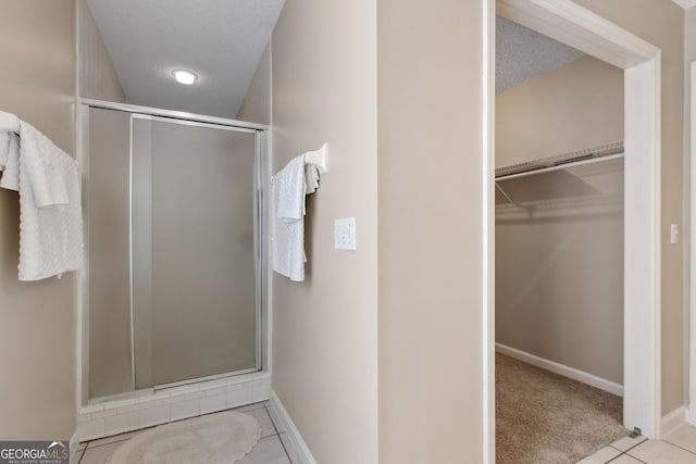 bathroom with a shower with door, tile patterned flooring, and a textured ceiling