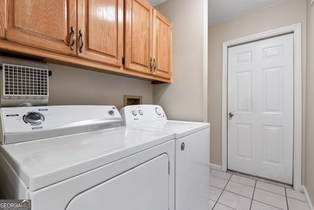 washroom with cabinets, washing machine and dryer, and light tile patterned floors