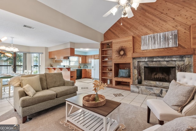 tiled living room featuring high vaulted ceiling, wooden walls, ceiling fan with notable chandelier, and a stone fireplace