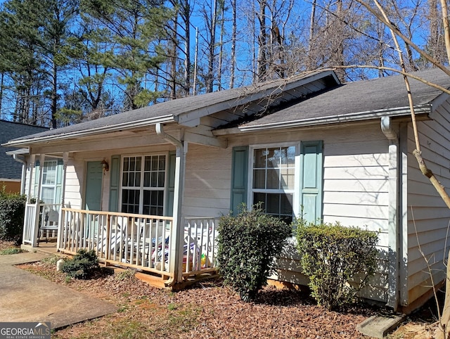 exterior space with a porch and roof with shingles