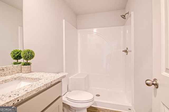 bathroom featuring vanity, a shower, and toilet