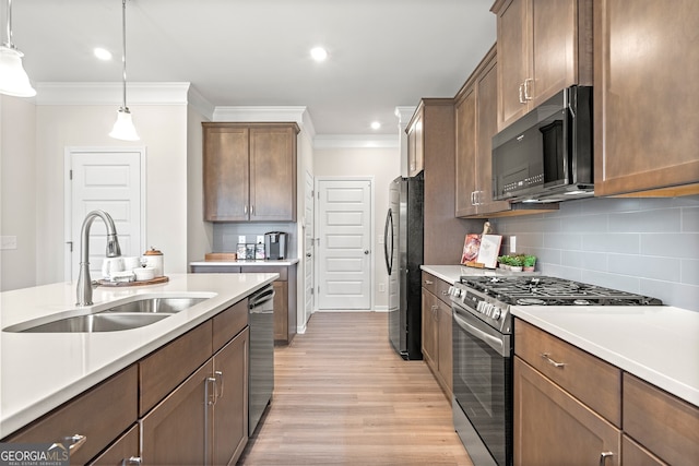 kitchen with crown molding, stainless steel appliances, decorative light fixtures, and sink