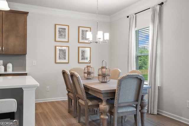 dining area with crown molding, an inviting chandelier, and light hardwood / wood-style floors