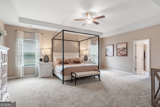 carpeted bedroom featuring a raised ceiling and ceiling fan