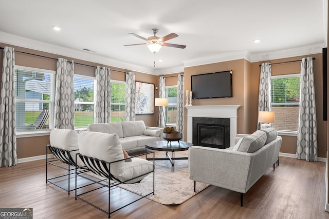 living room featuring hardwood / wood-style flooring, crown molding, a healthy amount of sunlight, and ceiling fan