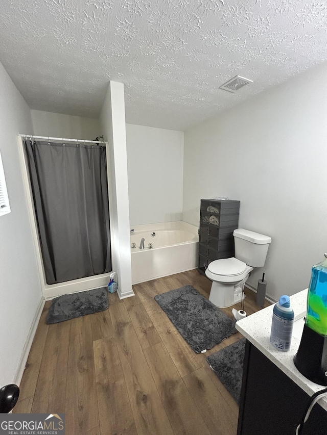 full bathroom featuring vanity, hardwood / wood-style flooring, a textured ceiling, and toilet