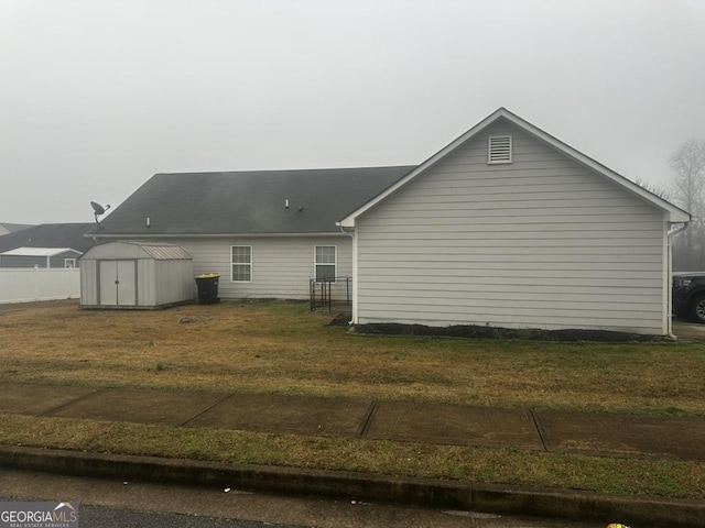 back of house with a lawn and a storage shed