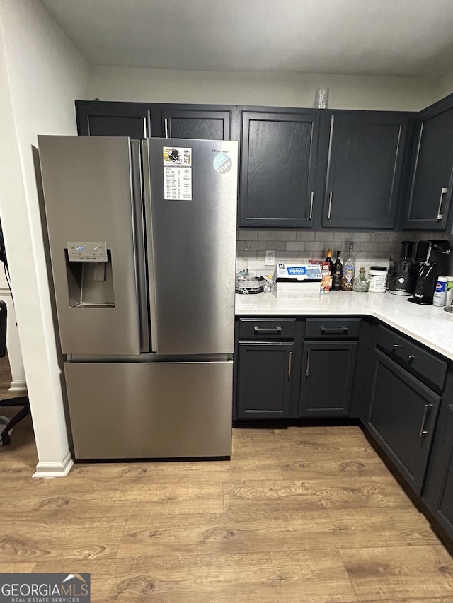 kitchen with decorative backsplash, stainless steel fridge, and light wood-type flooring