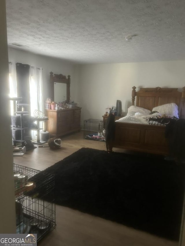 bedroom featuring hardwood / wood-style floors and a textured ceiling