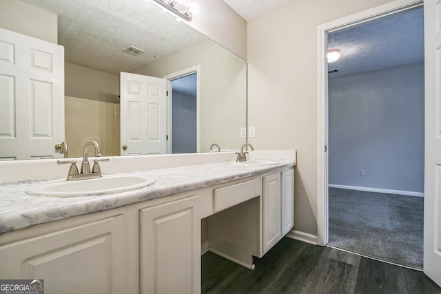 bathroom featuring hardwood / wood-style flooring, vanity, and a textured ceiling