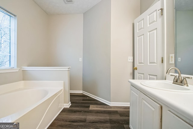 bathroom featuring vanity, hardwood / wood-style flooring, a bathing tub, and a textured ceiling