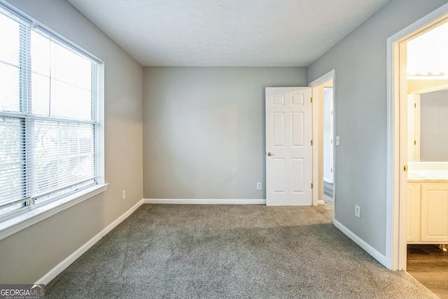 unfurnished bedroom with ensuite bath and carpet floors