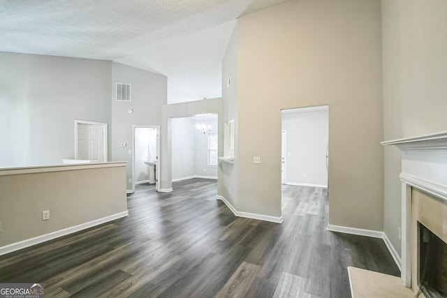 unfurnished living room featuring an inviting chandelier, sink, dark hardwood / wood-style floors, and high vaulted ceiling