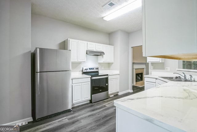 kitchen with stainless steel appliances, white cabinetry, light stone countertops, and hardwood / wood-style flooring