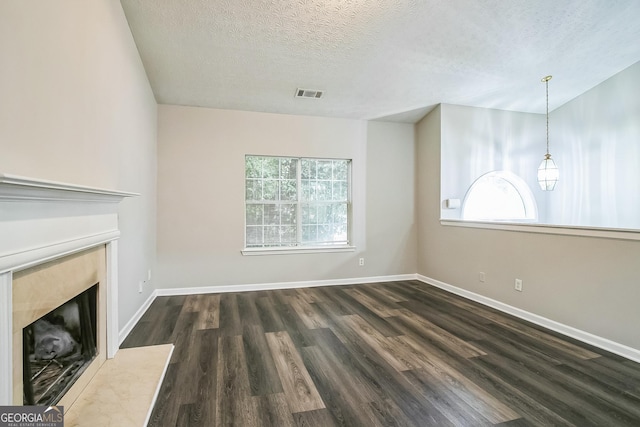 unfurnished living room featuring dark wood-type flooring and a textured ceiling