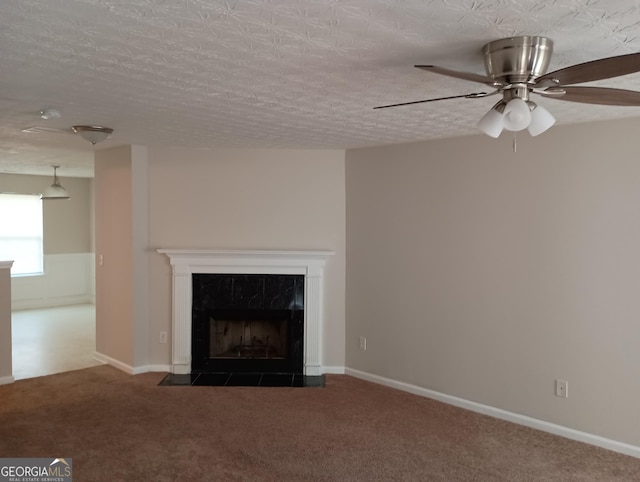 unfurnished living room with a fireplace, dark carpet, ceiling fan, a textured ceiling, and baseboards