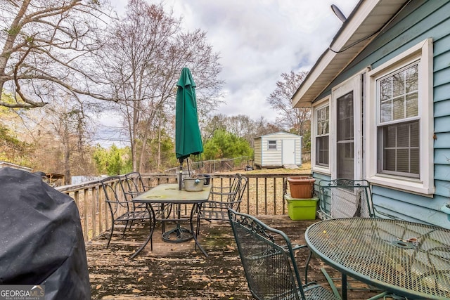 wooden deck featuring a storage shed and a grill