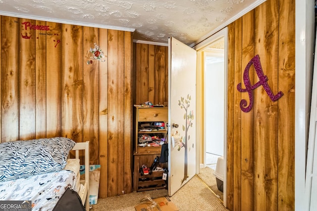 carpeted bedroom with ornamental molding, wooden walls, and a textured ceiling