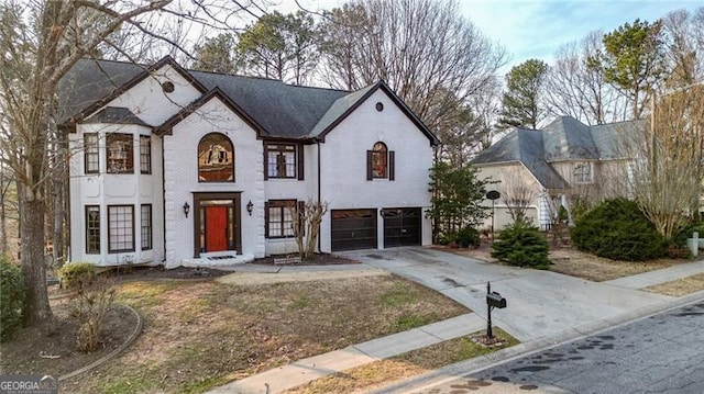 french country home with a garage, driveway, and brick siding