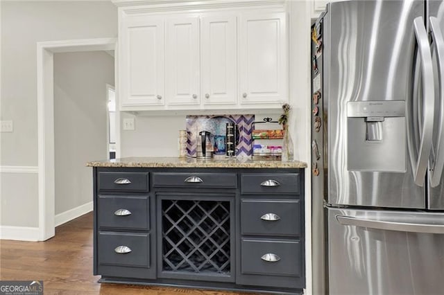 bar featuring stainless steel fridge, baseboards, tasteful backsplash, and dark wood-style flooring