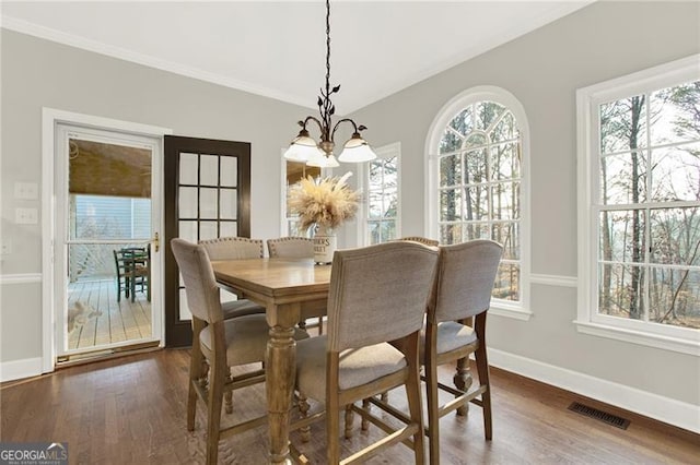 dining space featuring dark wood-style floors, a notable chandelier, visible vents, ornamental molding, and baseboards