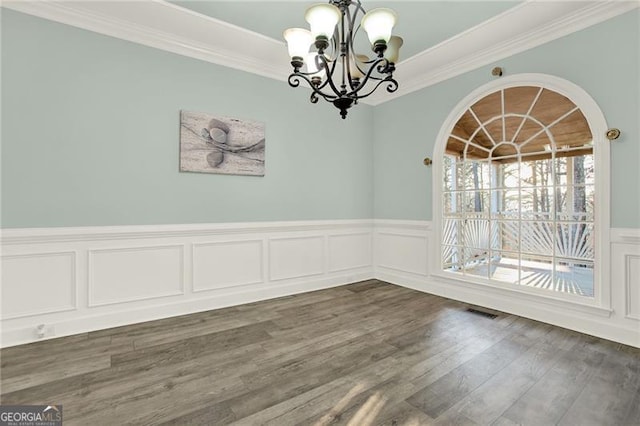 unfurnished dining area with dark wood-style floors, ornamental molding, visible vents, and an inviting chandelier