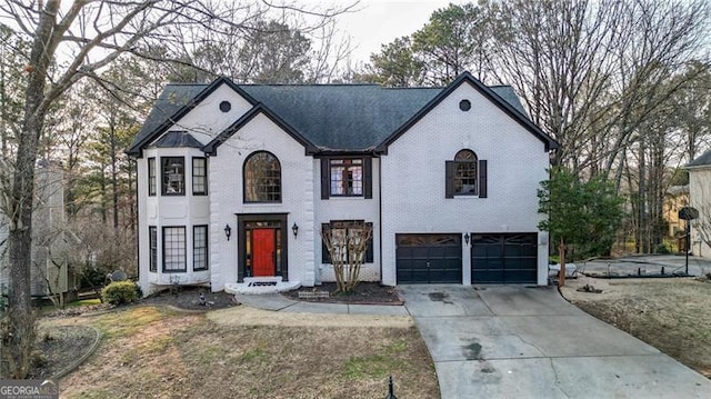 french provincial home featuring a garage, concrete driveway, brick siding, and a front lawn