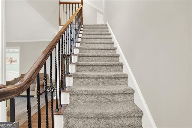 staircase with ornamental molding, wood finished floors, and baseboards