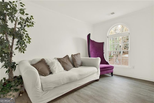 living area with wood finished floors, visible vents, and baseboards