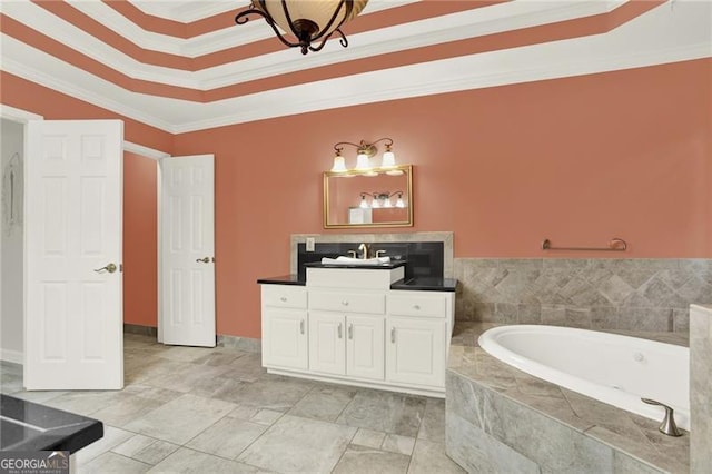 bathroom featuring a garden tub, ornamental molding, a raised ceiling, and vanity