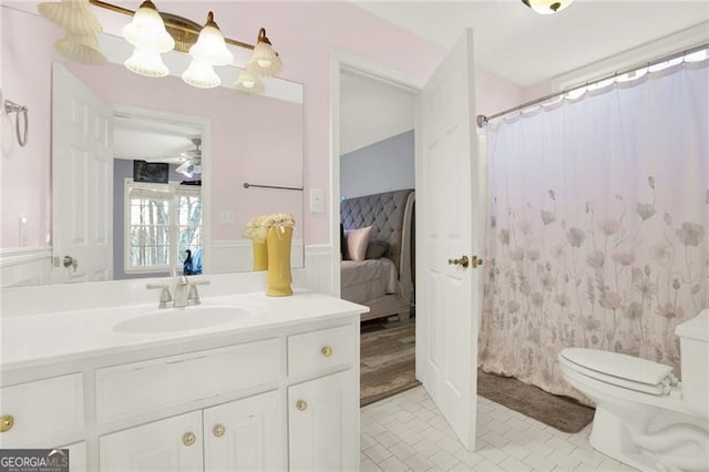 ensuite bathroom with a shower with shower curtain, toilet, wainscoting, vanity, and ensuite bath