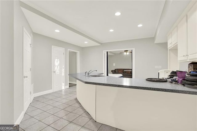 kitchen with light tile patterned floors, dark countertops, recessed lighting, white cabinets, and a sink