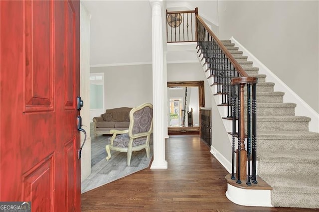 entrance foyer with decorative columns, baseboards, dark wood-style flooring, stairs, and crown molding