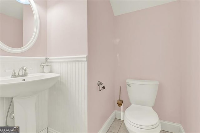 half bath with toilet, tile patterned flooring, and baseboards