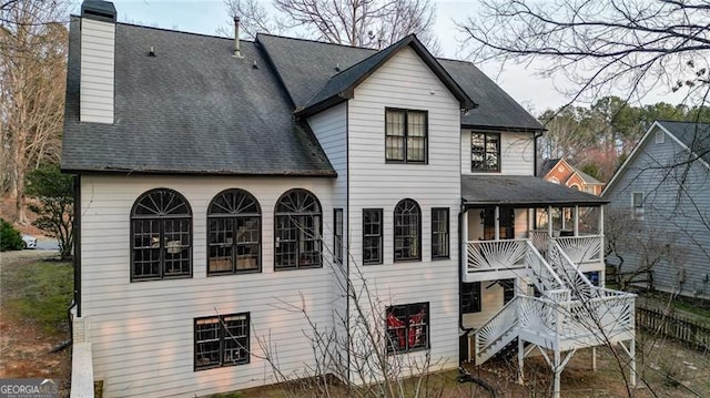 rear view of house featuring a chimney, covered porch, and stairway