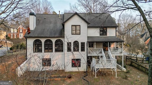 rear view of property featuring a chimney, fence, stairway, and a porch