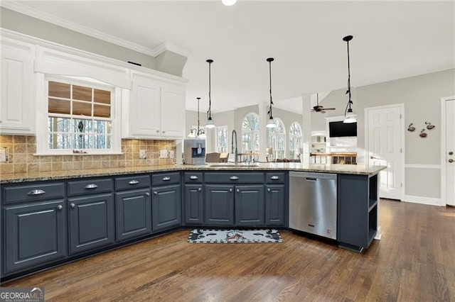 kitchen with stone countertops, dishwasher, decorative light fixtures, white cabinetry, and a sink