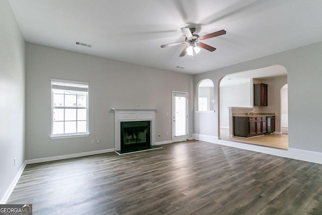 unfurnished living room featuring dark wood-type flooring and ceiling fan